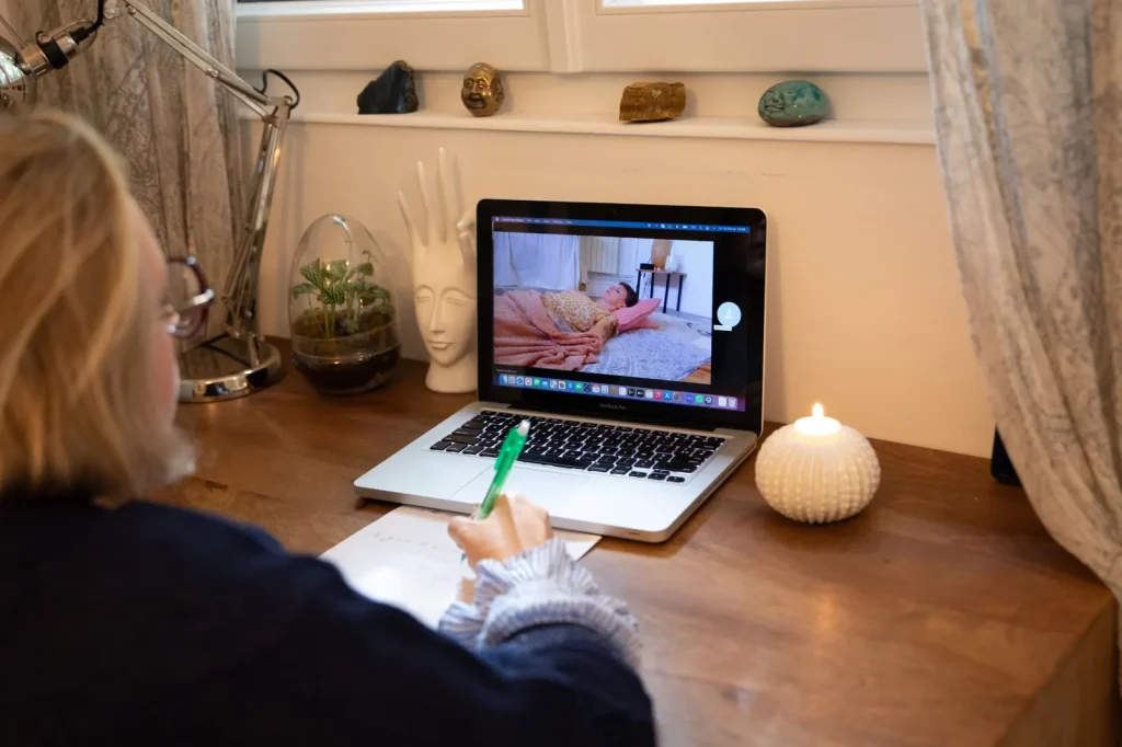 Marie guide une séance d'hypnose en visio, la personne allongée chez elle